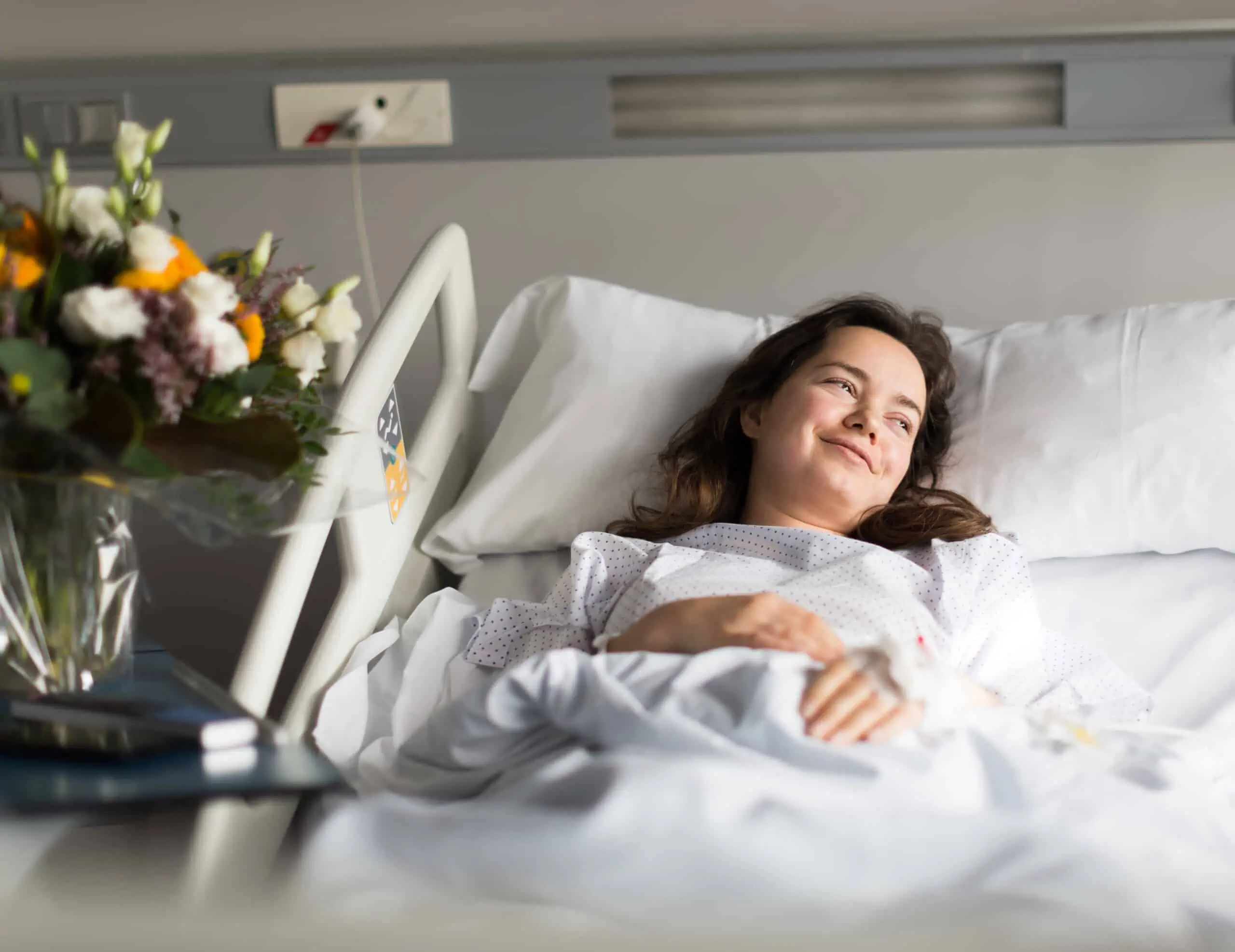 Patient looks happy in bed as she recovers from surgery